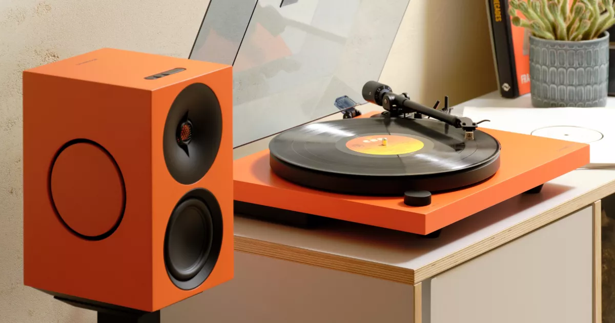 Оранжевый проигрыватель Cambridge Audio Spira рядом с активной колонкой