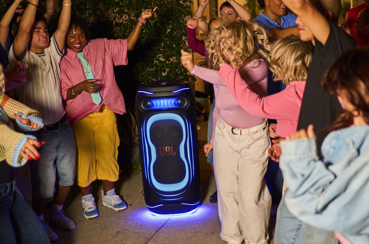 Акустическая система JBL PartyBox Ultimate 2 с включённой синей подсветкой среди танцующих людей
